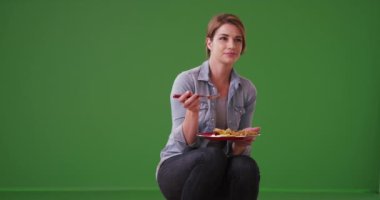 Yeşil ekranda yemeğini yiyen mutlu kadın. Anahtar ya da birleşik olmak üzere yeşil ekranda.