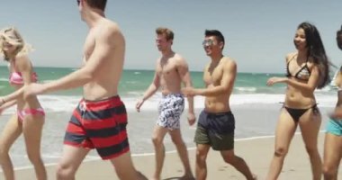 Irklar arası genç arkadaşlar sahilde yürüyor.