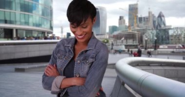 Kendinden emin genç siyahi kadın Londra, İngiltere 'de gururla poz veriyor. Kısa saçlı, kolları çapraz duran siyah kadın kameraya mutlu bir şekilde bakıyor. 4k