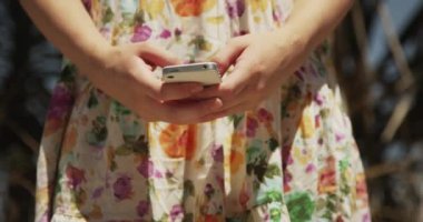 Açık havada akıllı telefondan mesaj atan kadın.