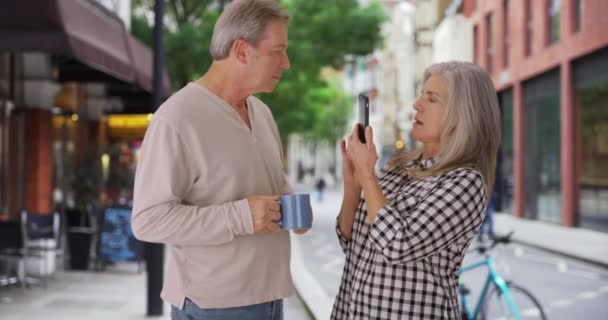 古い白い妻はイギリスでの休暇中に夫の写真を撮る 古い白人女性はロンドンの通りで彼女のパートナーを撮影します — ストック動画