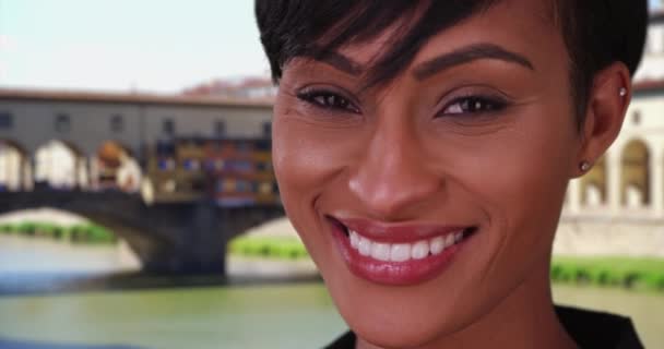 在意大利佛罗伦萨 一位美丽而快乐的黑人女性在镜头前微笑 佛罗伦萨Vecchio桥附近的混血女子兴高采烈地微笑着 — 图库视频影像