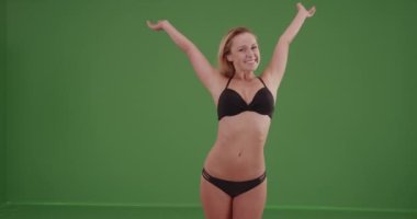 Yeşil ekranda bikinisiyle duran seksi kadın. Anahtar ya da birleşik olmak üzere yeşil ekranda.