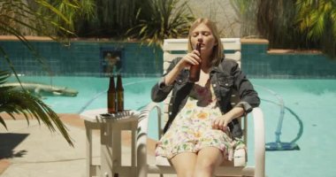 Havuz kenarında bira içen üzgün kadın.