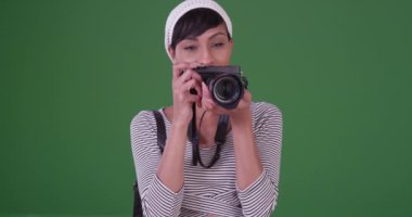 Kameralı bir kadın yeşil ekranda fotoğraflara bakıyor. Anahtar ya da birleşik olmak üzere yeşil ekranda.