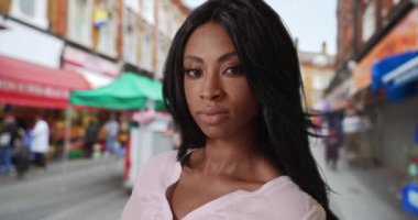 Açık hava pazarında duran çekici Afrikalı kadın kameraya özgüvenle bakıyor. Afro-Amerikalı kadın, Brixton 'daki kameraya sinsi sinsi bakıyor. 4k