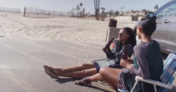 ビーチチェアに座ってビールを飲んで楽しい二人の黒のガールフレンド — ストック動画