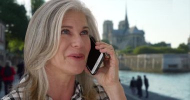 Yaşlı beyaz kadın Notre Dame yakınlarında akıllı telefonuyla dostça sohbet ediyor. Paris 'te gezen beyaz kadın, arkadaşından gelen çağrılara cevap veriyor. 4k