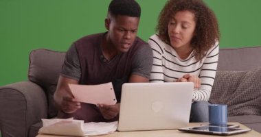 Afro-Amerikalı çift faturalarını yeşil ekranda dizüstü bilgisayarlarıyla ödüyor. Anahtar ya da birleşik olmak üzere yeşil ekranda.