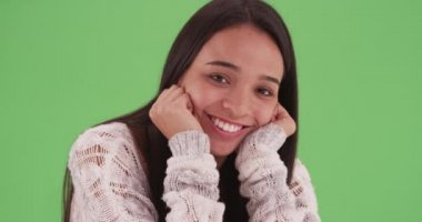 Genç Latin bir kadın yeşil ekranda yüzünü ekrana çeviriyor. Anahtar ya da birleşik olmak üzere yeşil ekranda.