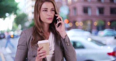 Genç iş kadını telefonda bir müşteriyle konuşuyor. Başarılı ve profesyonel bir kadın elinde kahve ve akıllı telefonla konuşuyor.