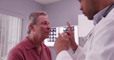 Afrikalı-Amerikalı doktor üst düzey beyaz hastanın kafa travması incelenmesi