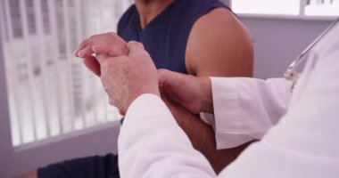 Orta yaşlı bir doktor, Afrikalı-Amerikalı bir atletin yaralı bileğini inceliyor.
