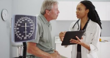 Siyah kadın doktor ofisi üst düzey hastayla konuşuyor
