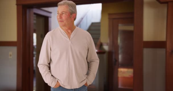 成熟したシニア白人男性の家の周りを見回す 幸せな中年の男立って周りを見回す家のリビングルーム — ストック動画