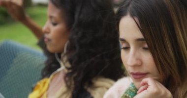 Güzel kadınlar bankta müzik dinliyor.
