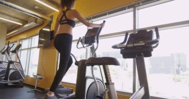 İspanyol kadın spor salonunda eliptik egzersiz makinesinde çalışıyor.