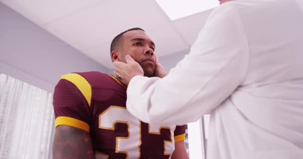 高齢の医者半ば首の負傷をスポーツのフットボール選手をチェック — ストック動画