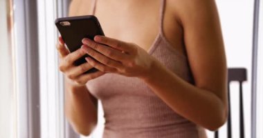 Evde akıllı telefon kullanan çekici bir kadın. Cep telefonunda internete göz atan kadın portresi.