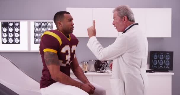 スポーツ傷害を持っている良い外見の選手はシニア医師によってレビュー — ストック動画