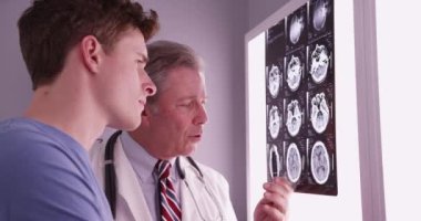 Yakışıklı beyaz bir erkek, doktorla röntgenlere bakıyor.