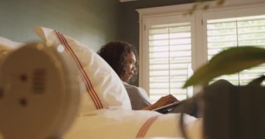 Yatakta dizüstü bilgisayar kullanan güzel Afrikalı kadın.