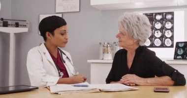 Genç bayan radyoloji uzmanı ve röntgen çeken yaşlı bir bayan hasta.