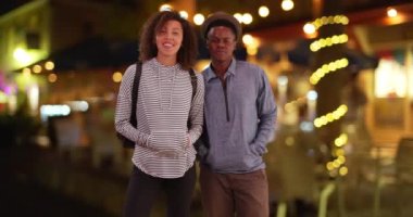 Afrika kökenli Amerikalı çiftler gece bir restoranın önünde konuşuyorlar. Siyahi adam ve kadın bir kafenin önünde taksi mi bekliyor? Geceleyin. 4k.