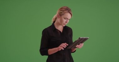 İş kadını yeşil ekranda tablet kullanıyor. Anahtar ya da birleşik olmak üzere yeşil ekranda.