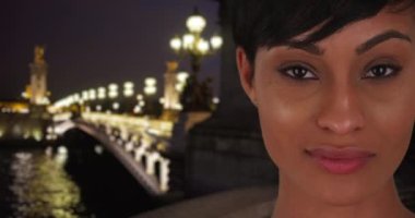 Paris 'teki Pont Alexandre III' ün yanındaki kameraya dikkatle bakan muhteşem melez genç bayan. Göz kamaştırıcı genç bayan Paris 'te bir gecede kameraya tutkuyla bakıyor. 4k