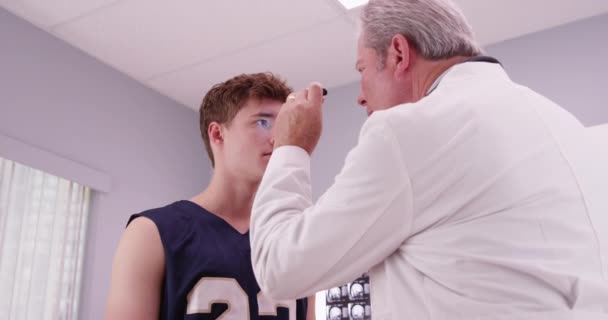 Médico Senior Revisando Los Ojos Del Jugador Baloncesto Con Linterna — Vídeos de Stock