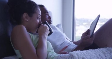 Siyah ve Latin çift sabahları tablet bilgisayar kullanırken kahve içiyorlar.