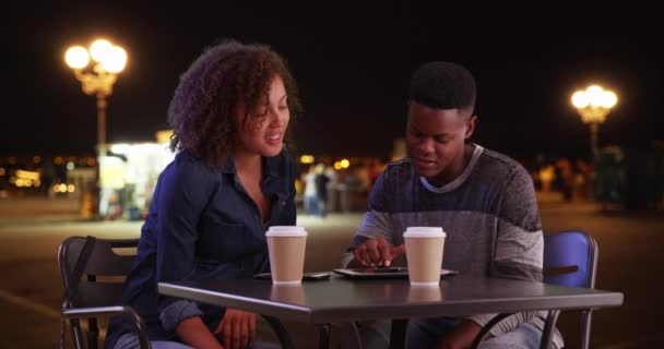 黑人男女晚上坐在外面用触摸屏装置 非裔美国男人和女人聚在一起喝咖啡 聊天和使用技术 — 图库视频影像
