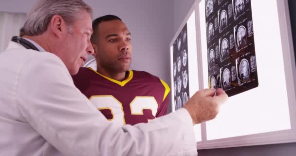 Afrikanischer Sportler Schaut Sich Mit Kaukasischem Arzt Röntgenbilder — Stockvideo