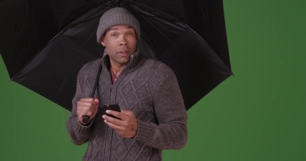 一个黑人站在绿幕上 手里拿着一把伞 在绿色屏幕上键入或合成 — 图库视频影像