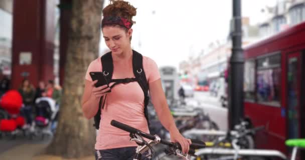 适合高加索女性骑自行车的人在伦敦街上通过短信与朋友交谈 迷人的白人女人从自行车上休息一下 发一条短信 — 图库视频影像