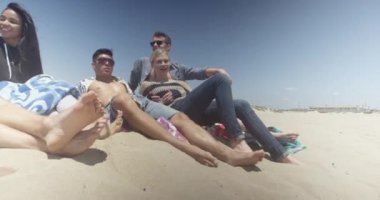 Beaech 'in üzerinde oturan modern, çok ırklı genç arkadaşların portresi.