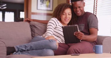 Milenyum çifti kanepede oturup tablet bilgisayarlarında film izliyor. İki Afro-Amerikan kendi bloknotlarında bir video izliyor. Oturma odasındaki kanepede siyah bir çift yan yana yatıyor. 4k