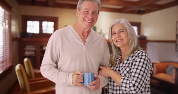 素敵なシニアカップル笑顔 家のキッチンの中に立っている 幸せな中年の夫と妻がお互いの会社を楽しんで — ストック動画
