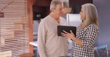 Tablet cihazına bakan yaşlı bir çiftin portresi. Güzel yaşlı beyaz çift tablet bilgisayar okuyor..