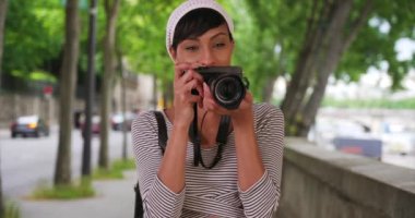 Dışarıda fotoğraf çeken güzel Afrikalı kadın kamerasındaki son fotoğrafa bakıyor. Modern siyahi yaratıcı kadın şehrin dışında fotoğraf çekiyor. 4k