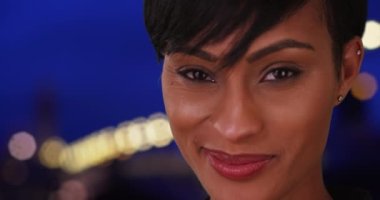Neşeli siyah kadın güzel bir akşamda dışarıda kameraya bakıyor. Genç, güzel, Afrikalı ve Latin melez bir kadın kameraya gelişigüzel bakıyor. 4k