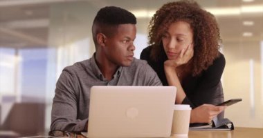 Modern bir ofiste dizüstü bilgisayarda çalışan iki siyah iş adamı. Afrika kökenli Amerikalı profesyoneller elinde telefon tutarken dizüstü bilgisayarda çalışıyorlar. Siyah milenyumlar çağdaş bir ofiste bilgisayara bakarlar.