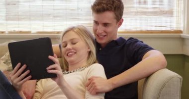 Kanepede tablet kullanan güzel genç bir çift.