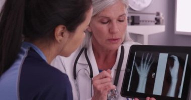 Genç, çekici bir futbolcu kadın bir doktorla el bilgisayarı tabletindeki röntgenlere bakıyor.