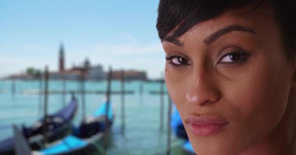 ヴェネツィアの魅力的な短髪黒の女性は イタリアは真剣にカメラを見ています ヴェネツィアを旅する神秘的なアフリカの女性は 海岸によって官能的に見つめている — ストック動画