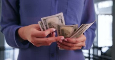 Genç başarılı iş kadını parasını modern bir iş binasında sayıyor. Hevesli bayan girişimci en son kazandıklarını sayıyor. 4k