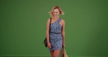 Beyaz elbiseli ve güneş şapkalı bir kadın yeşil ekranda kameraya doğru yürüyor. Anahtar ya da birleşik olmak üzere yeşil ekranda.