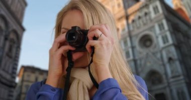 Floransa, İtalya 'yı gezen mutlu genç turist dijital kamerasıyla eve dönen insanlara fotoğraf çekiyor. Beyaz, sarışın bir kadın Floransa Katedrali 'nin yakınındaki kamerasında anılarını yakalıyor. 4k
