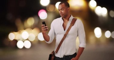 Genç bir siyah adam cep telefonuyla video kaydediyor. Afrikalı Amerikalı bir yetişkin sosyal medyaya göndermek için akıllı telefonunu kullanıyor. 4k